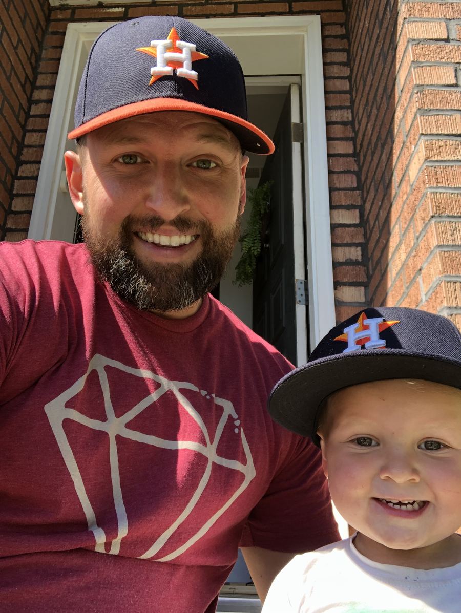 Katy Junk Crew owner and his son smiling in Astros caps outside a brick Katy-area home